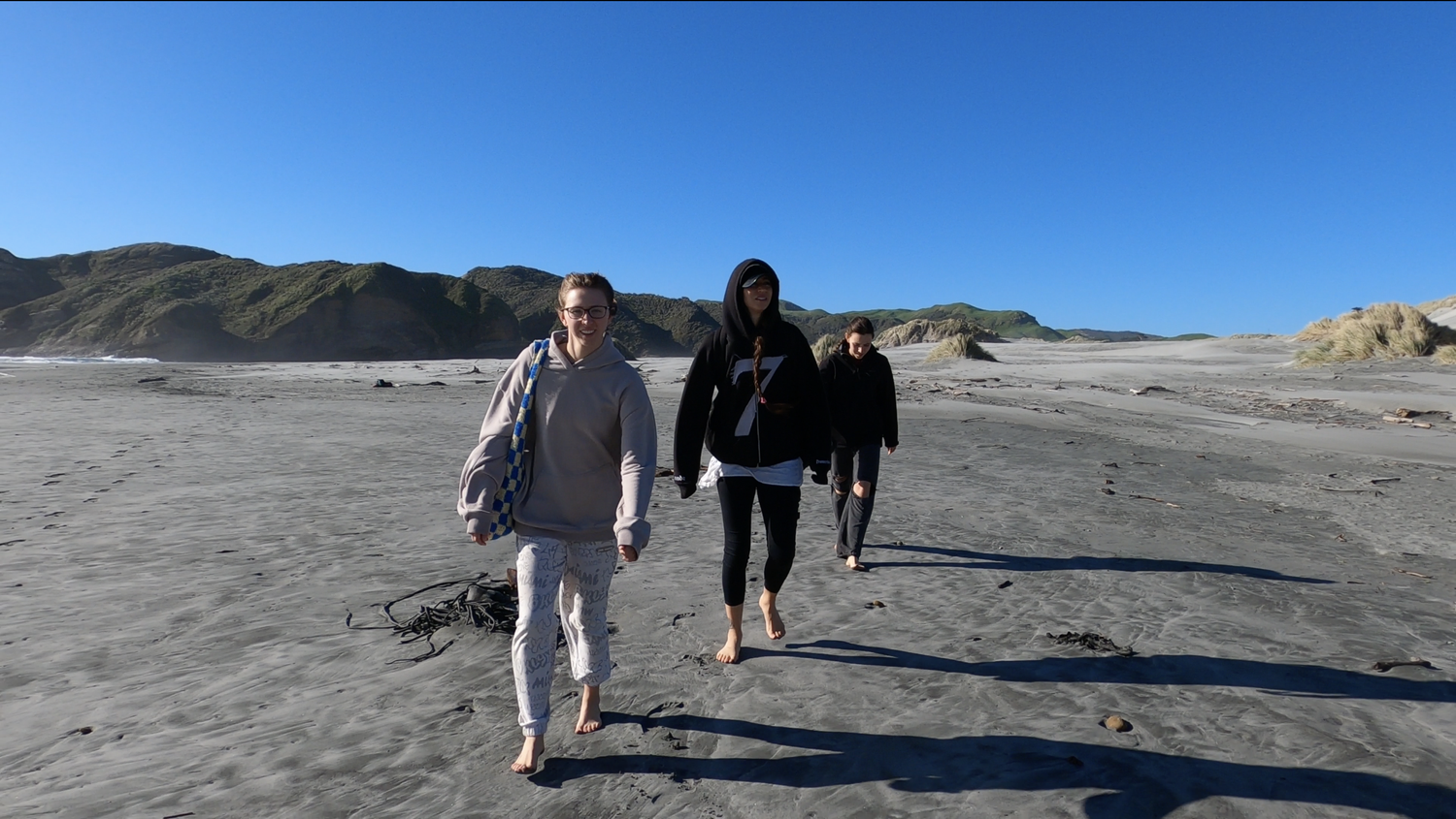 Our family walking barefoot across Wharariki Beach
