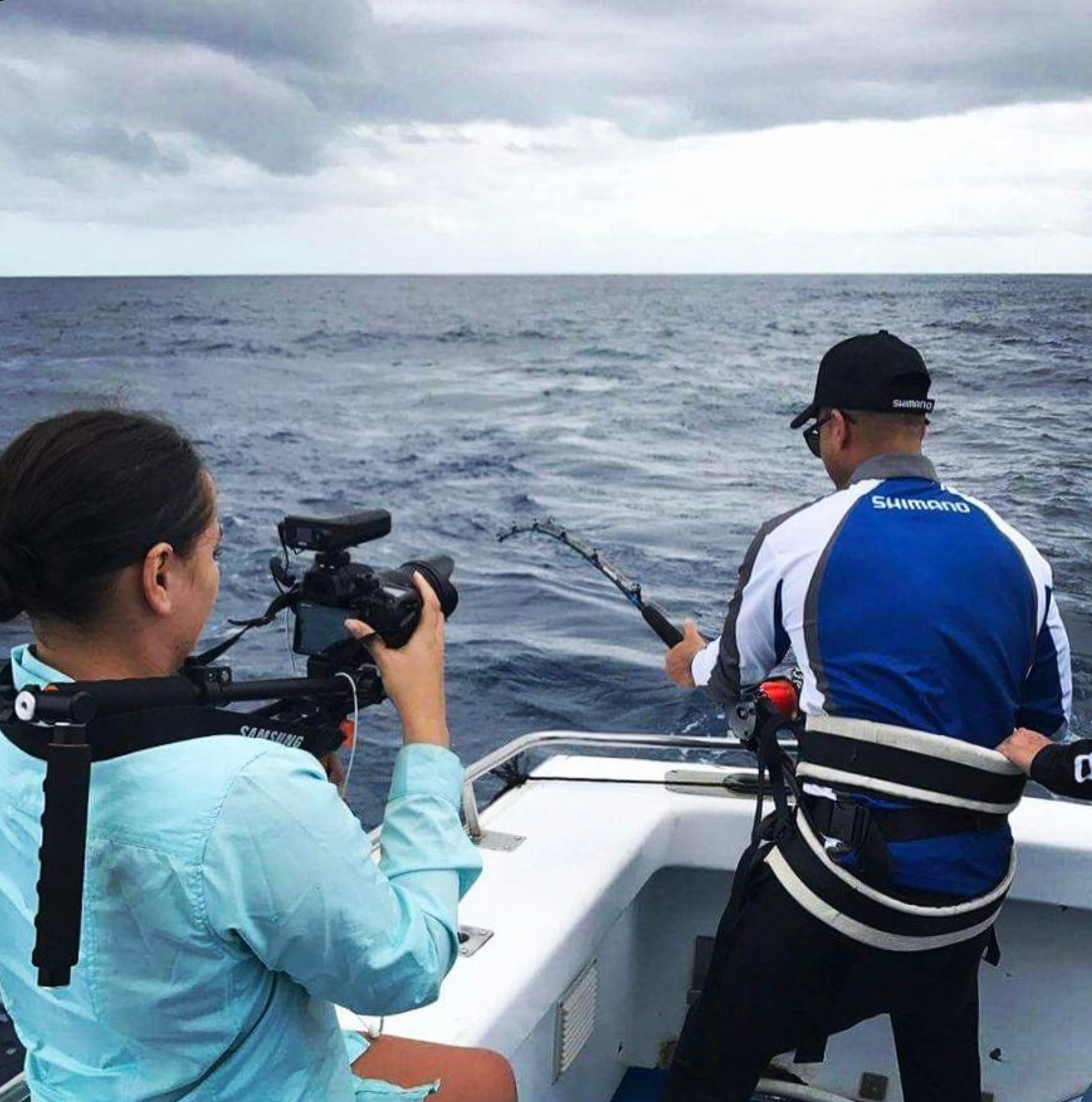 Tash Armstrong operating a camera on a shoulder rig while filming Guy Sebastian fishing from a boat for Shimano.