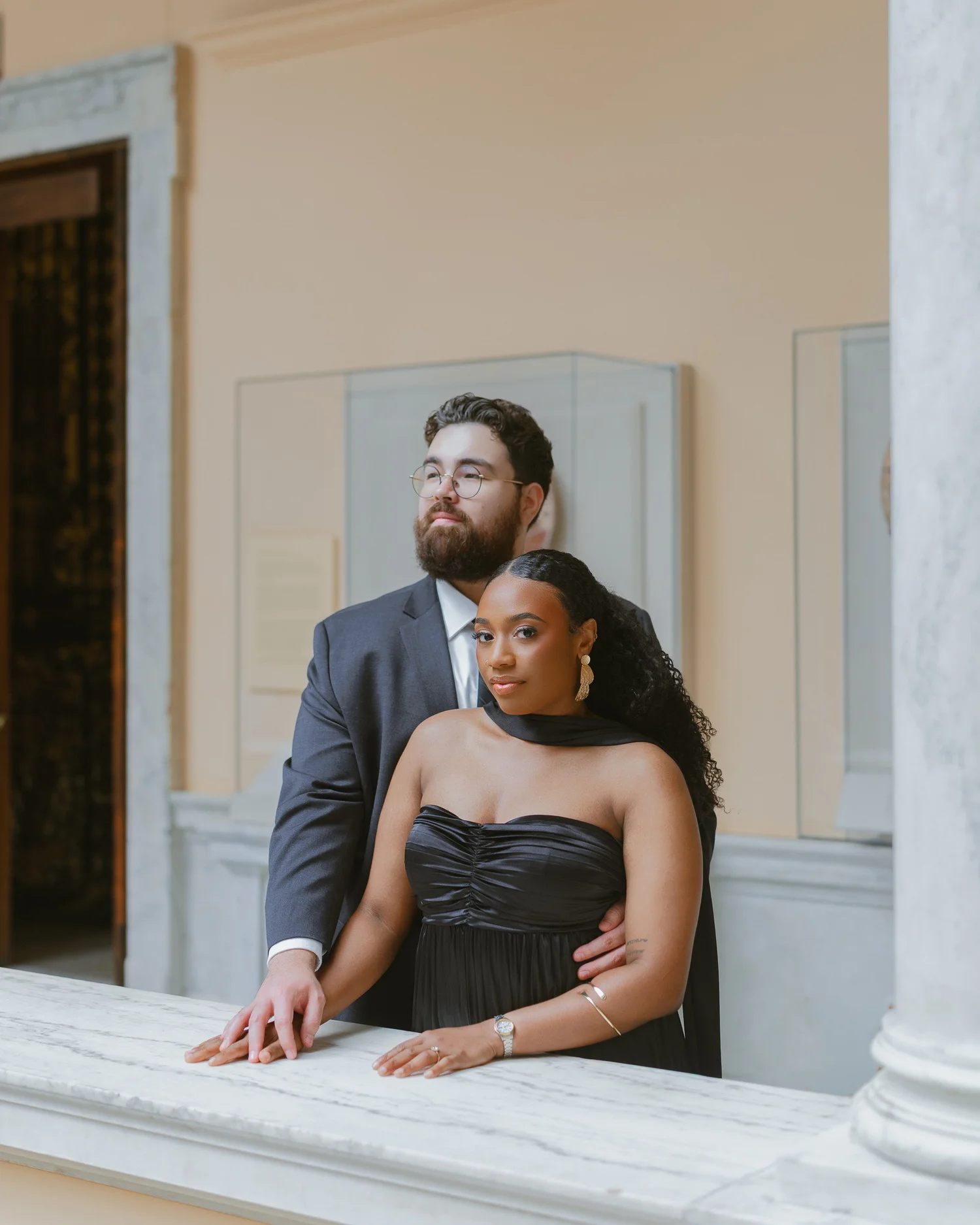 Couple embracing behind a pale marble railing.