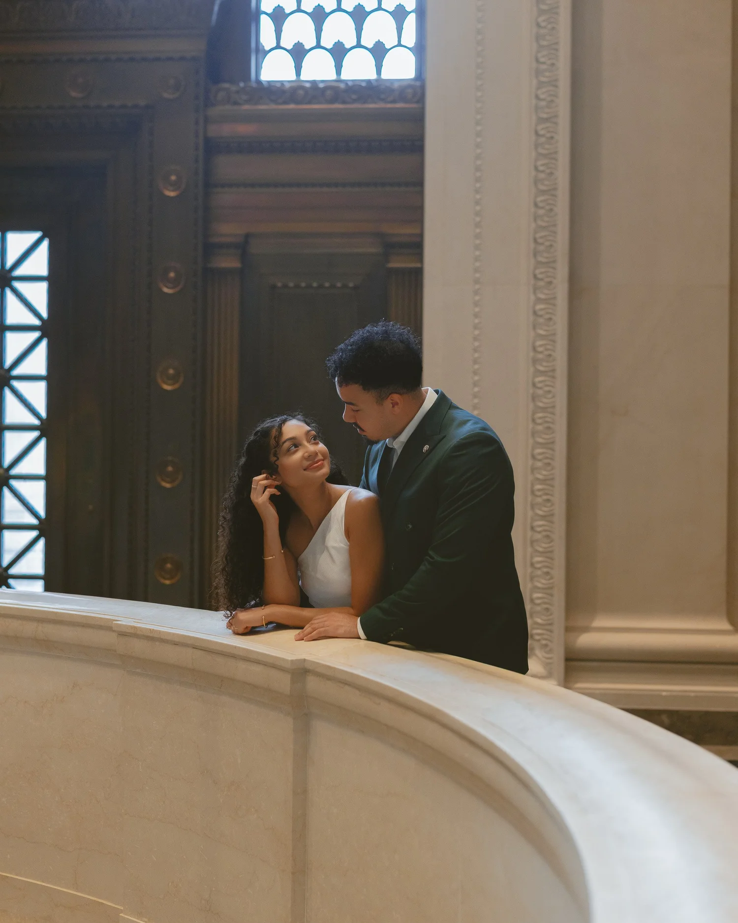 Couple exchanging a look over a curved marble balustrade.