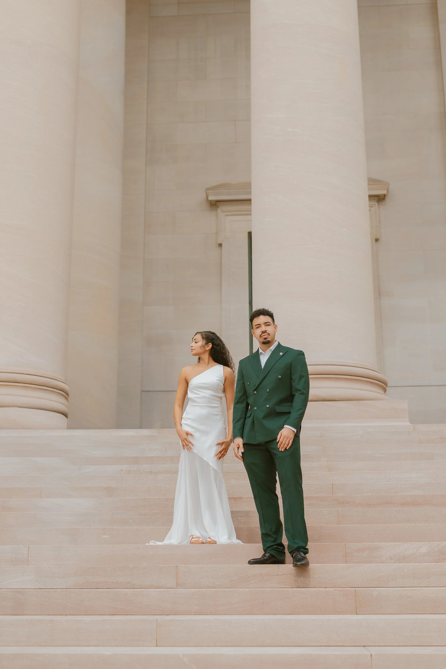 Couple standing together on stone steps beside a tall column.