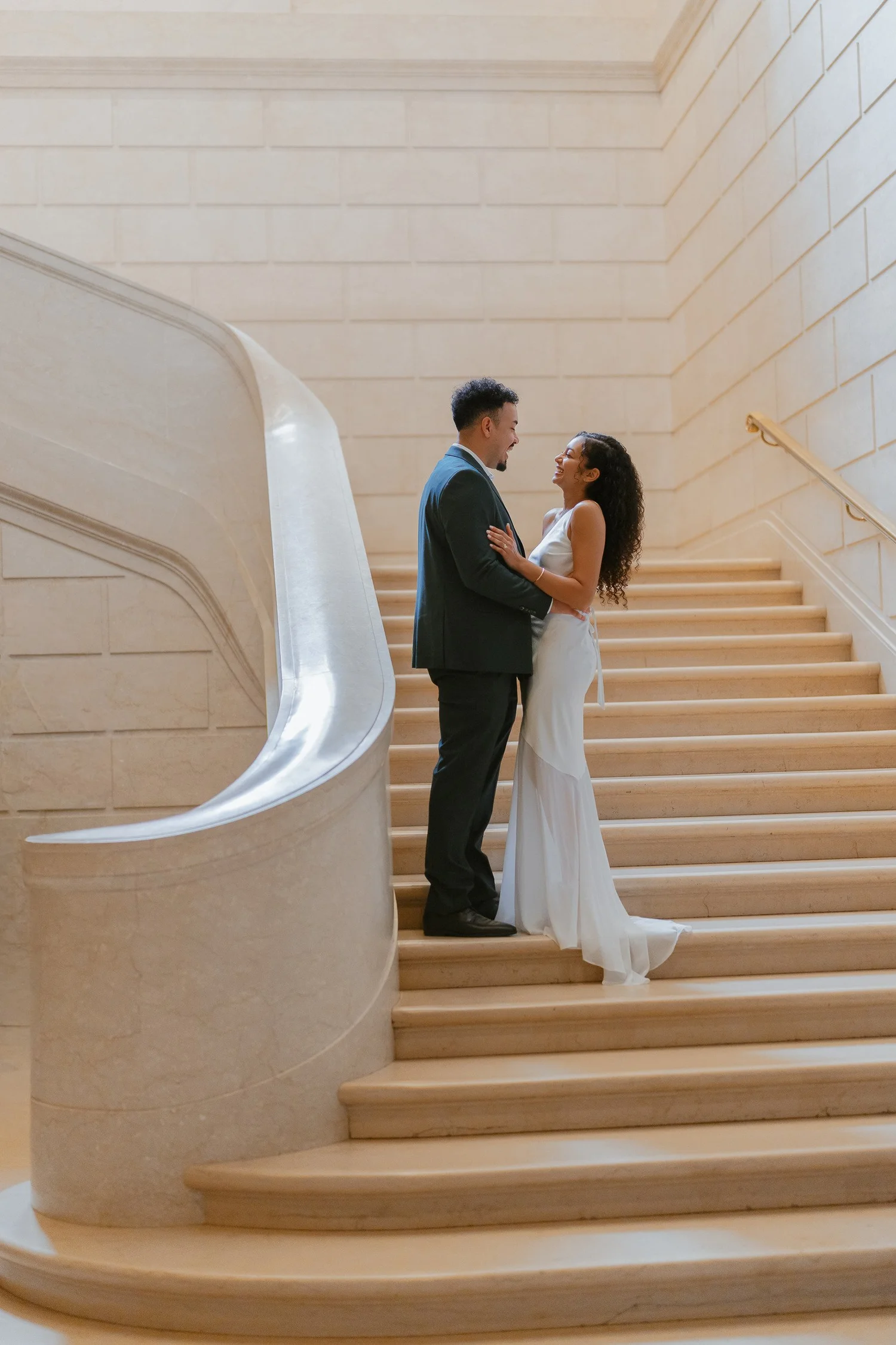 Couple sharing a quiet moment on a curved marble staircase.