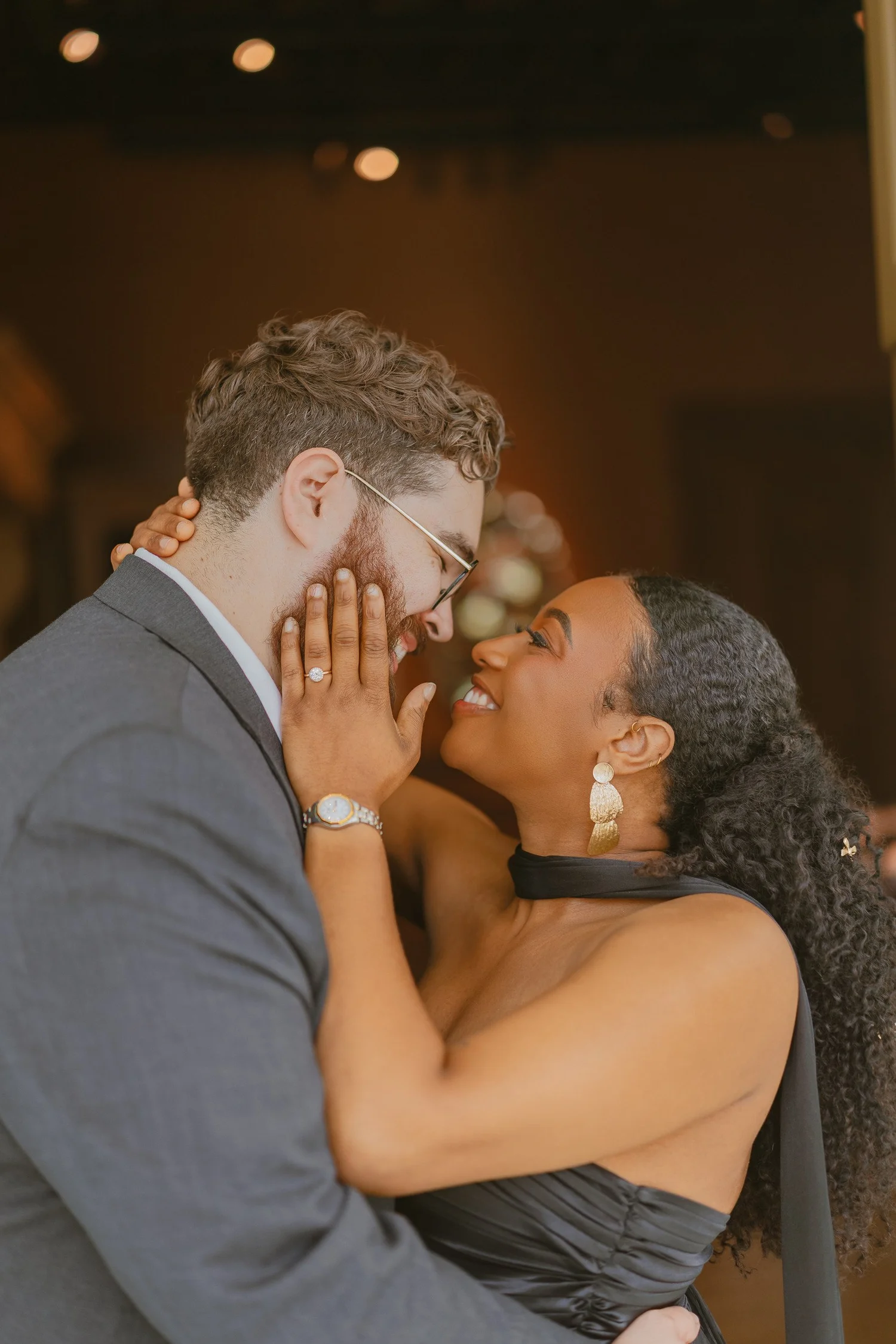 Close-up of a smiling couple leaning together in a warmly lit doorway.