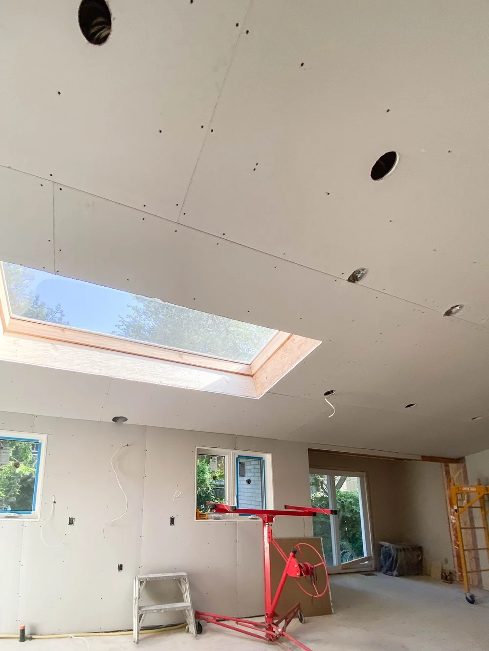 Boarded ceiling around a skylight with a drywall lift below