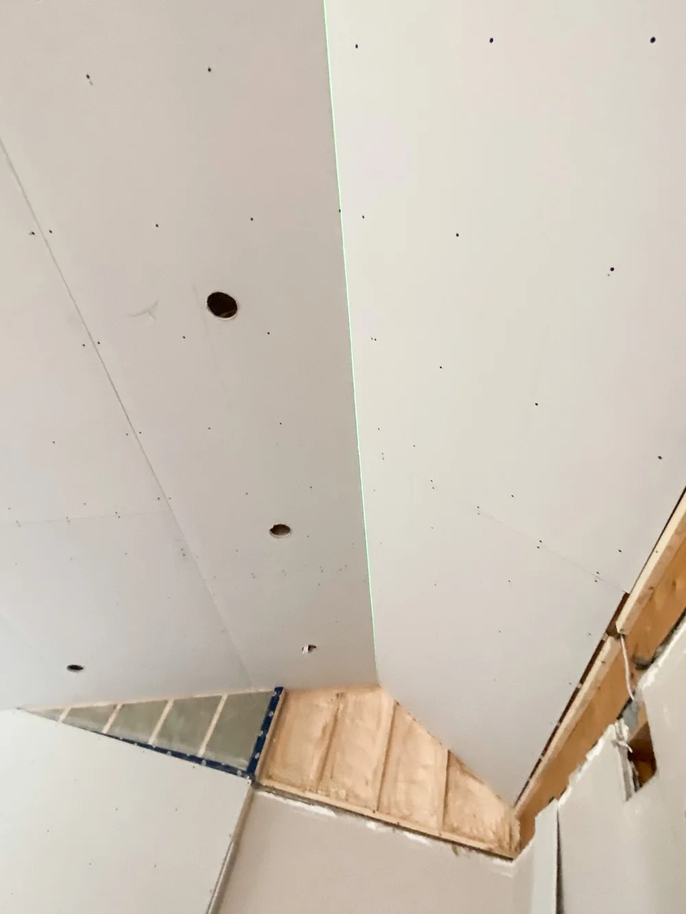 Ceiling drywall detail with a green laser alignment line