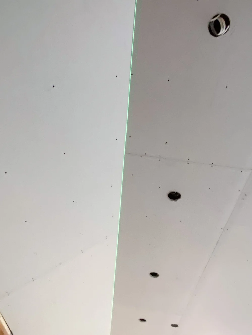 Drywall ceiling seams and recessed-light cutouts under a laser line