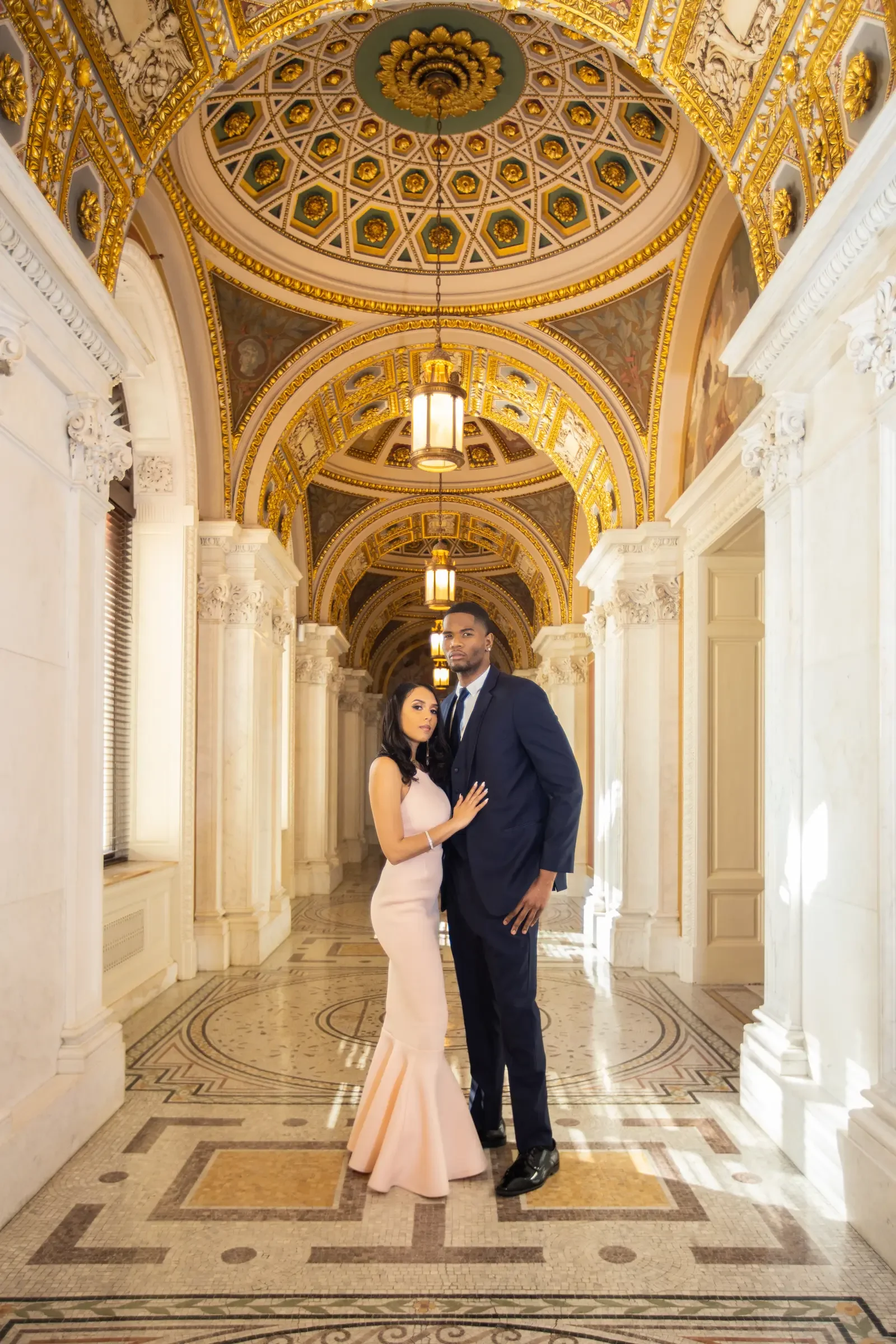 Alicia and Ted framed by an ornate architectural corridor