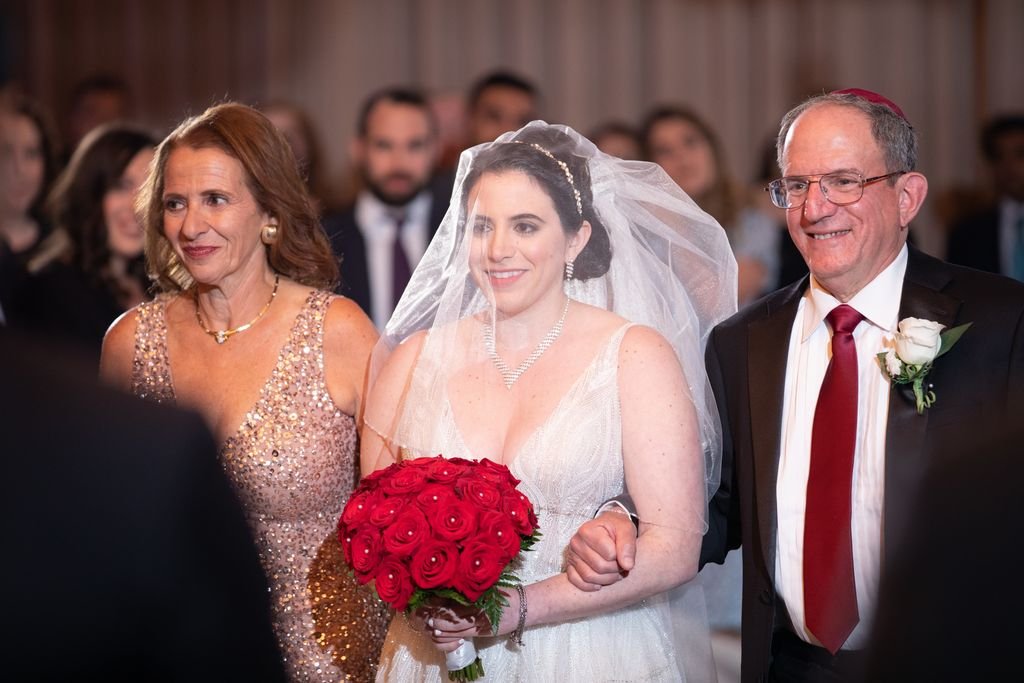A bride walking down the aisle with her parents