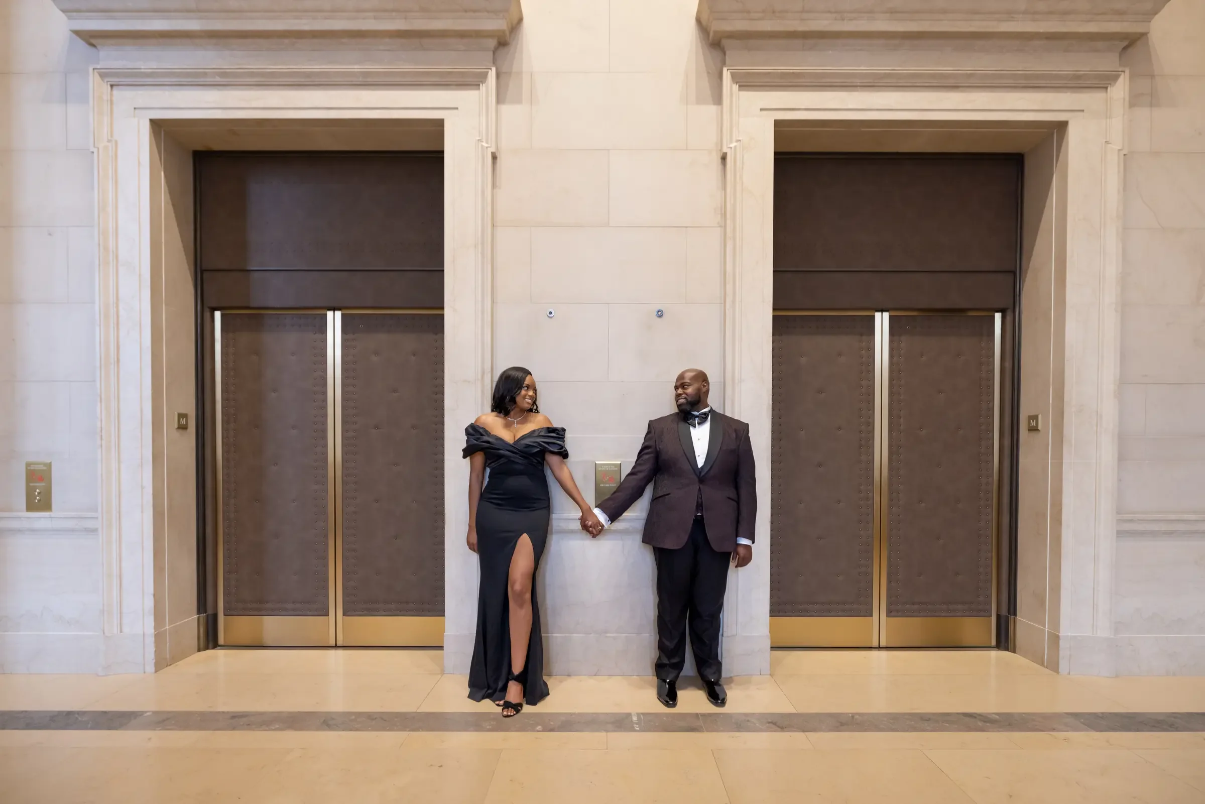 Aria and Tavon holding hands in a symmetrical architectural setting