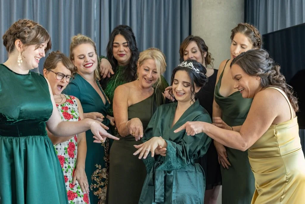 A bride laughing with her wedding party while getting ready