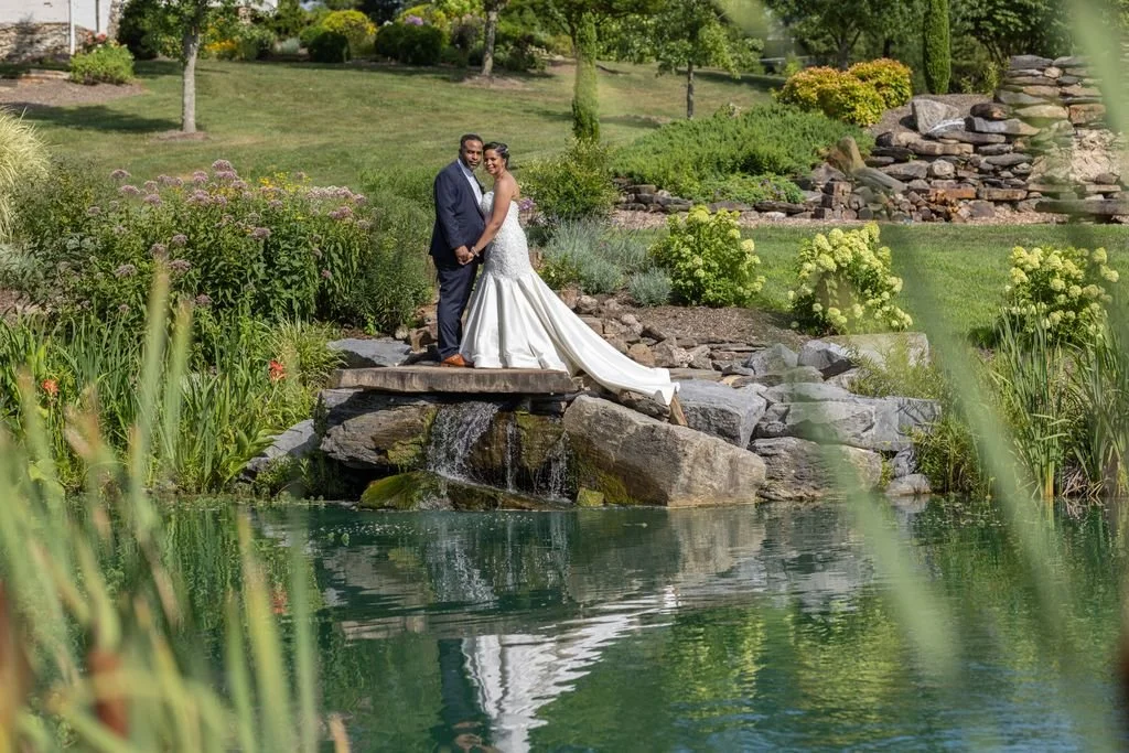 A wedding couple reflected beside a landscaped pond