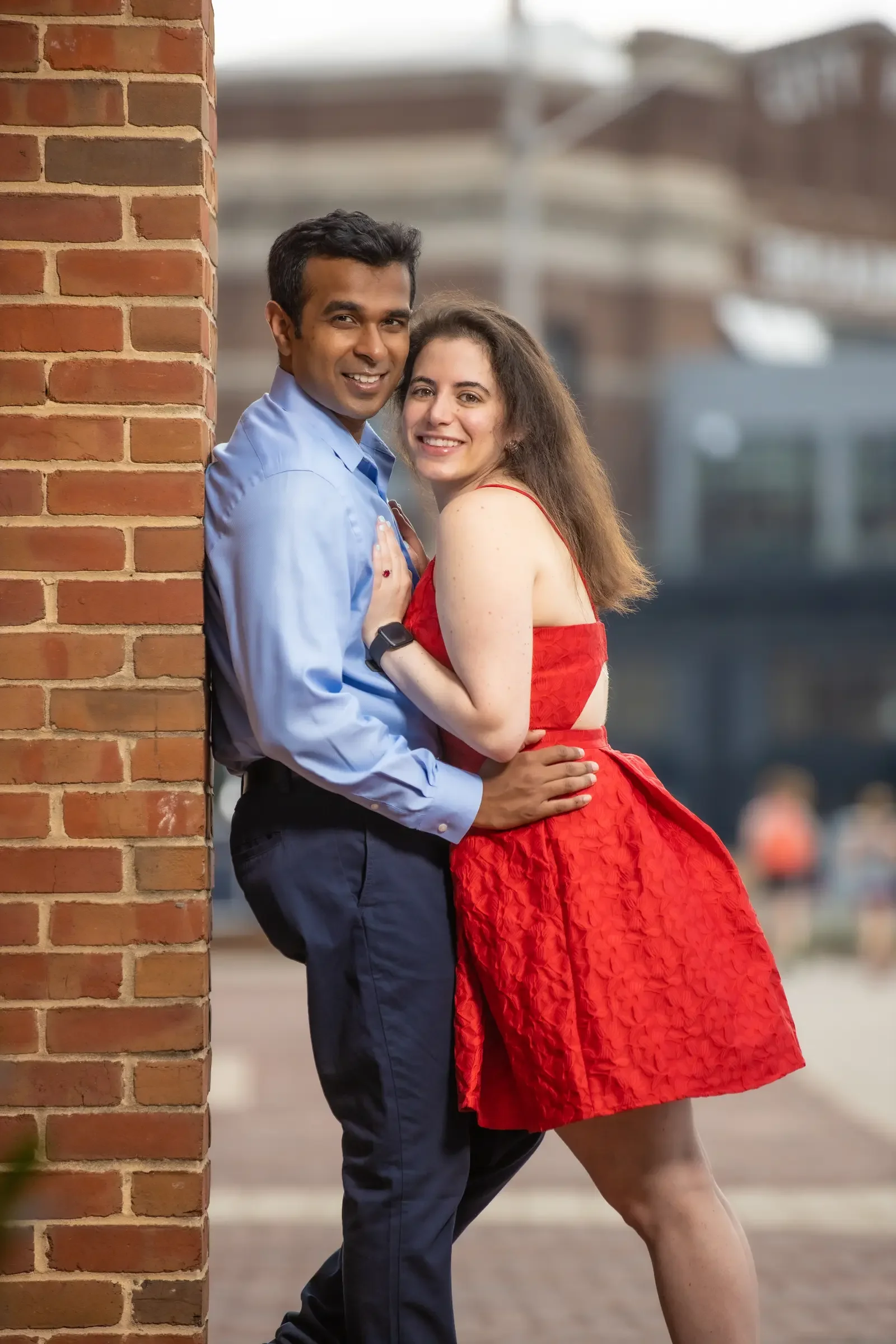 Mallory and Gabe embracing beside a brick wall in Baltimore