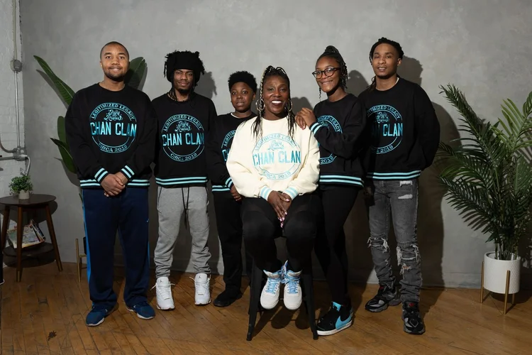 Zaria Chandler seated in the center of five young people wearing Chan Clan sweatshirts in a photo studio