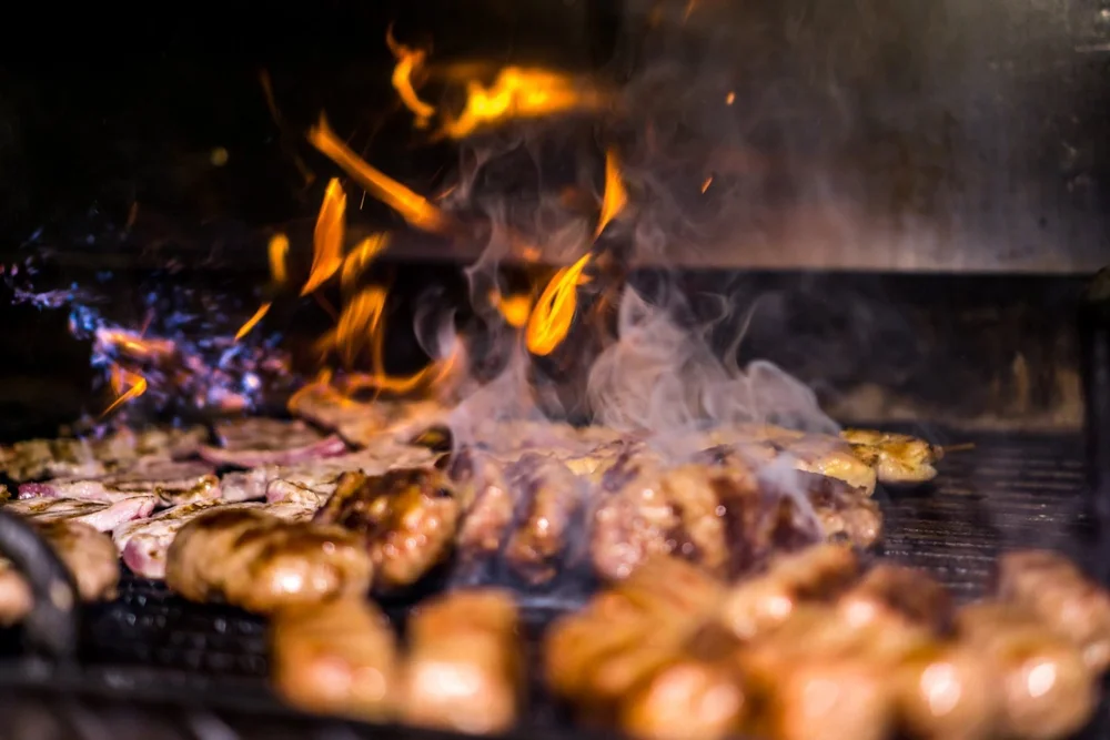 Meats grilling over open charcoal flame