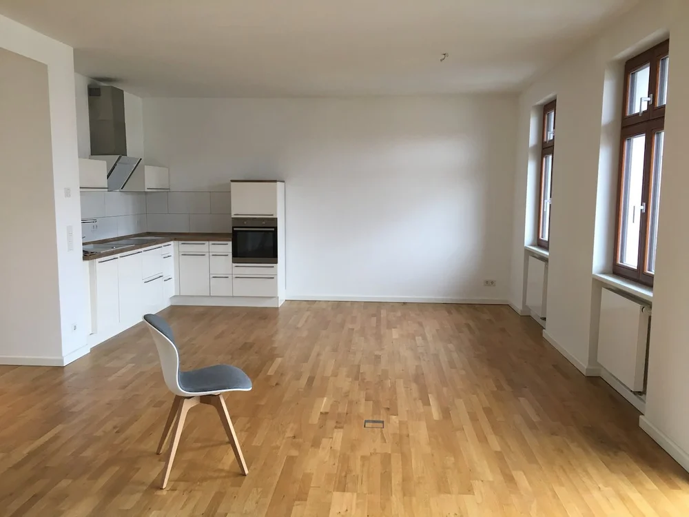 Empty apartment with a fitted kitchen and wood floor