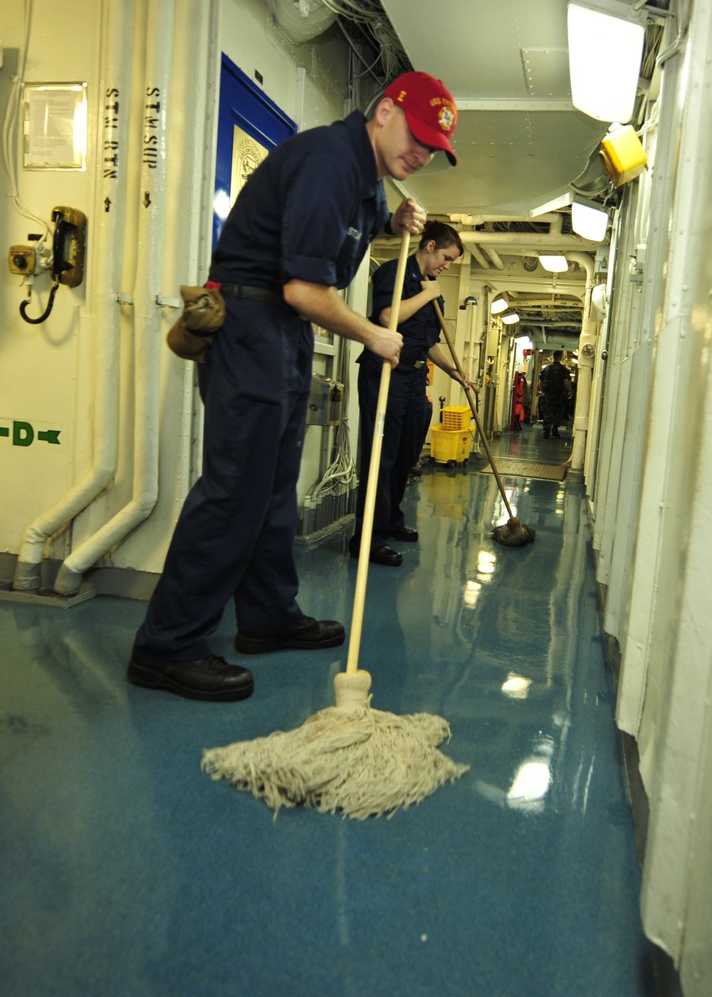 Worker mopping a hard floor in a corridor