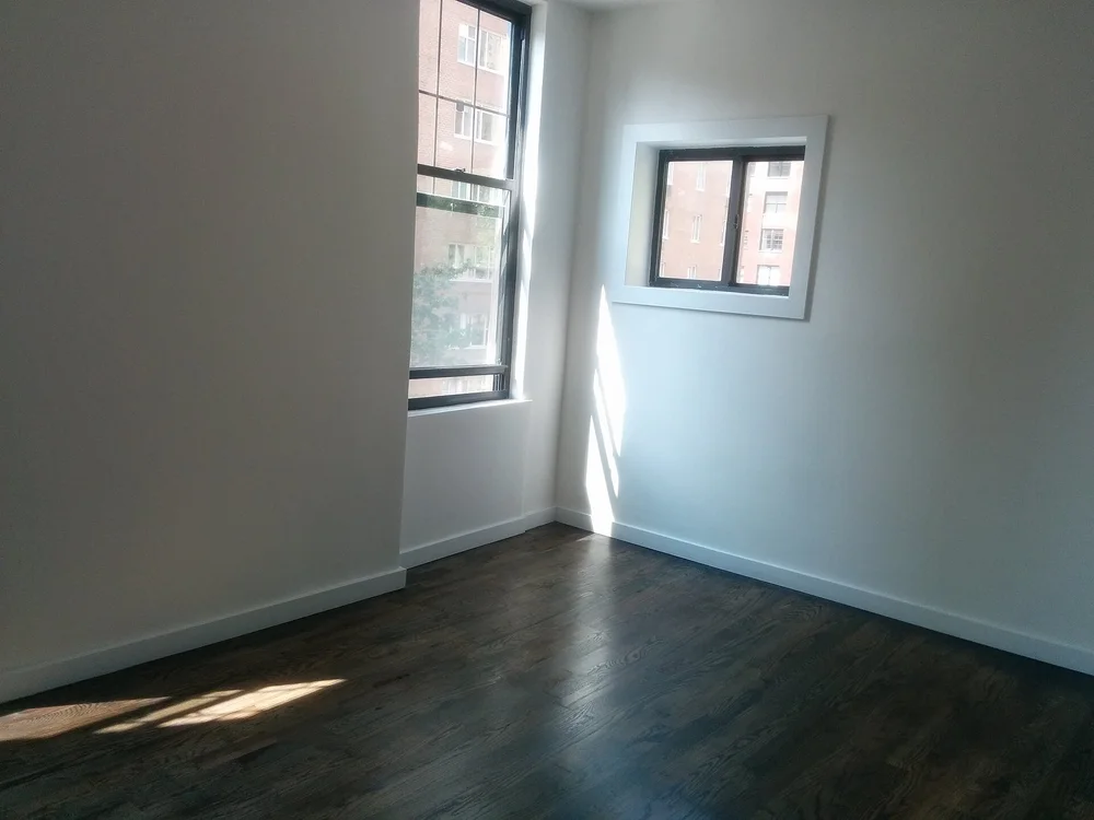 Empty apartment room with a window and bare walls