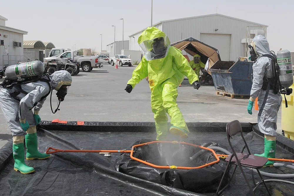 Workers in protective suits and respirators at an outdoor decontamination station