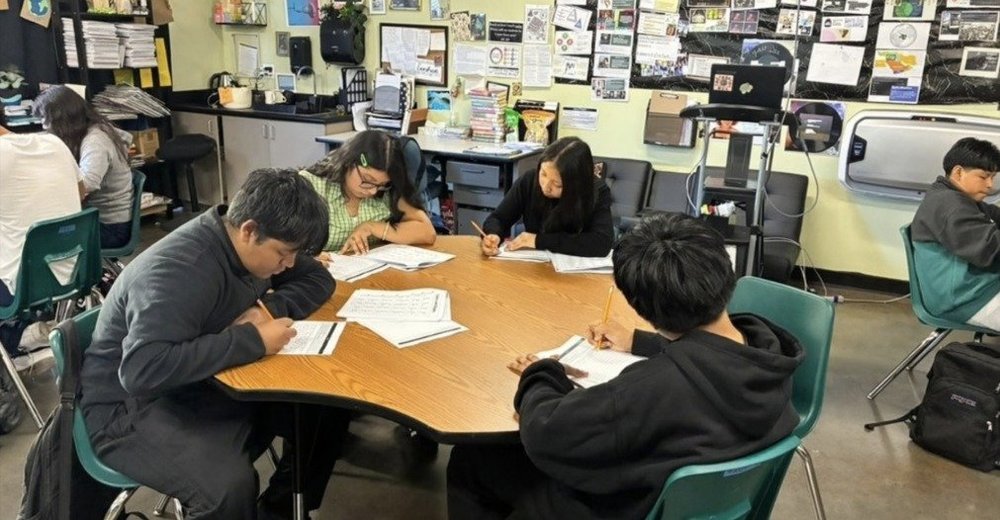 ARISE English 1 students writing at a table